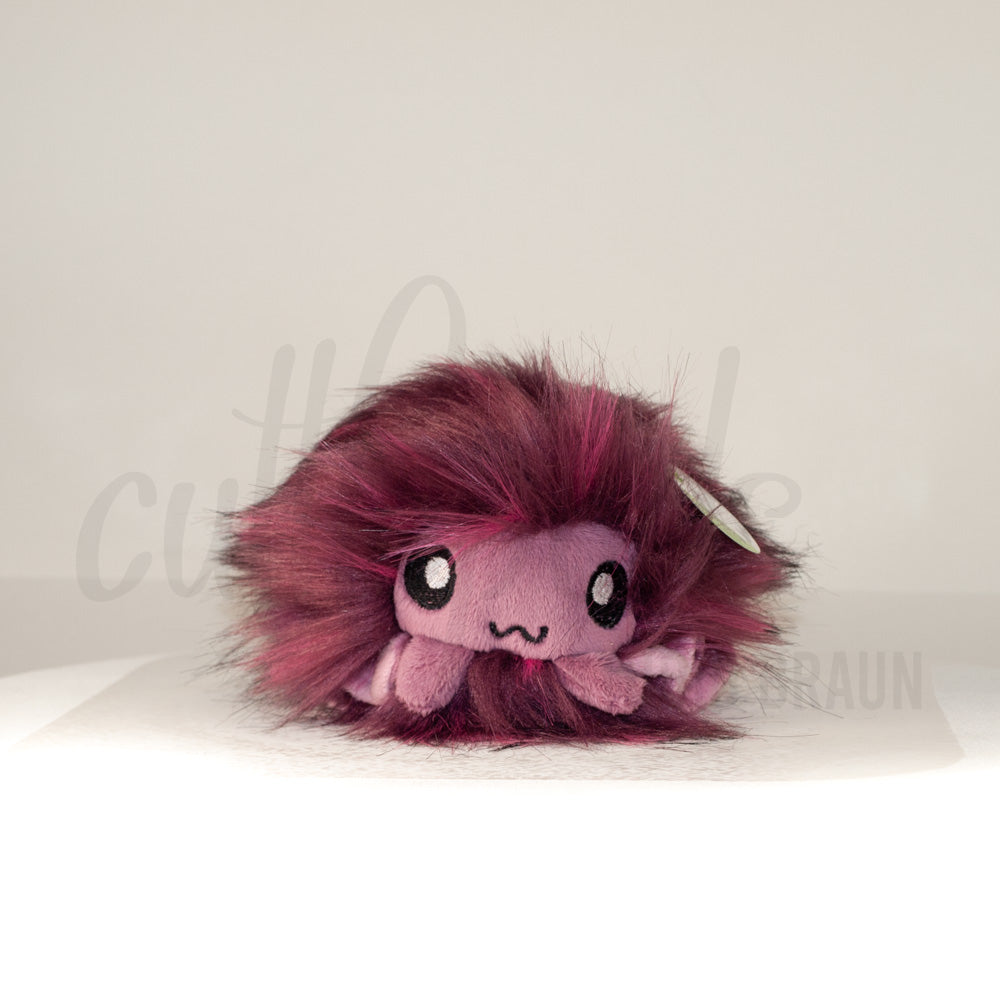 Front view of a cuttlepod plush toy, showcasing its unique form with large, cartoonish eyes, ruffled fins, and a cuddly, furry texture.