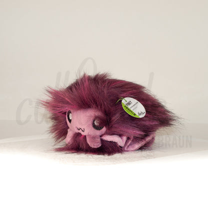 Front view of a cuttlepod plush toy, captured at a slight angle to highlight its charming features: large, cartoonish eyes, ruffled fins, and a cuddly, furry texture.