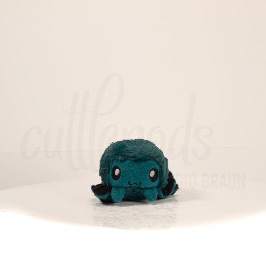 Front view of a cuttlepod plush toy, showcasing its unique form with large, cartoonish eyes, ruffled fins, and a cuddly, furry texture.