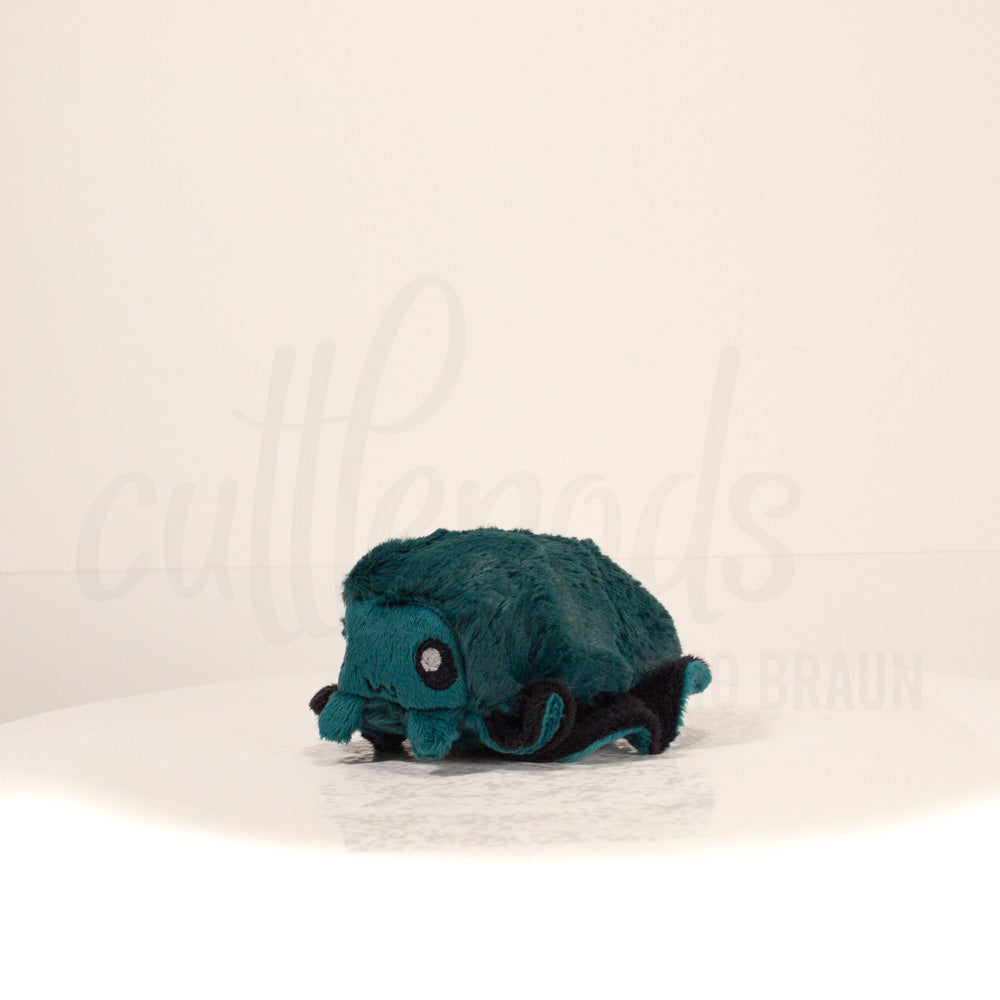 Front view of a cuttlepod plush toy, captured at a slight angle to highlight its charming features: large, cartoonish eyes, ruffled fins, and a cuddly, furry texture.