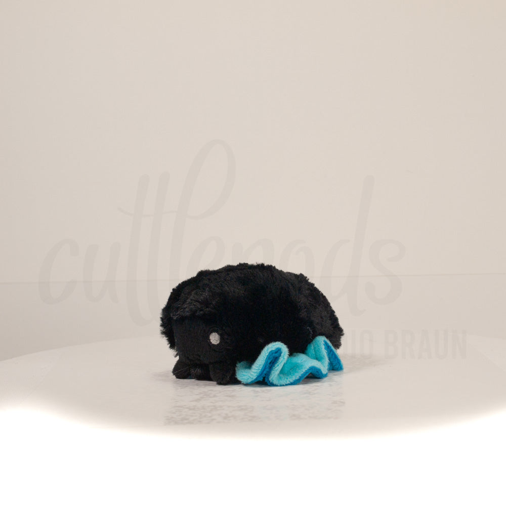 Front view of a cuttlepod plush toy, captured at a slight angle to highlight its charming features: large, cartoonish eyes, ruffled fins, and a cuddly, furry texture.