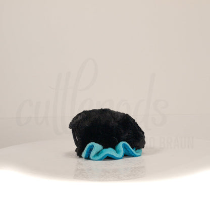 Side profile view of a cuttlepod plush toy, showcasing two-tone ruffled fins, and a cuddly, furry body.