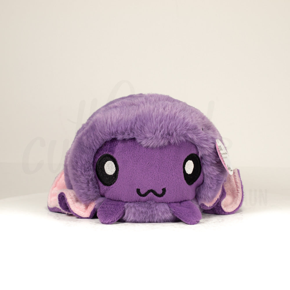 Front view of a cuttlepod plush toy, showcasing its unique form with large, cartoonish eyes, ruffled fins, and a cuddly, furry texture.