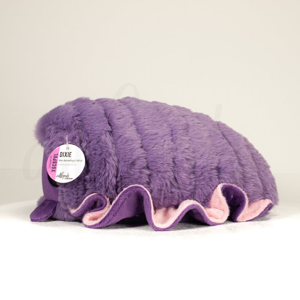 Side profile view of a cuttlepod plush toy, showcasing two-tone ruffled fins, and a cuddly, furry body.