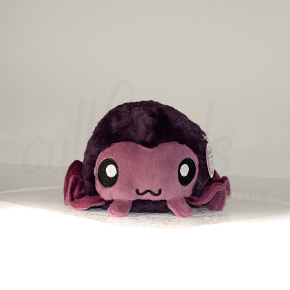 Front view of a cuttlepod plush toy, showcasing its unique form with large, cartoonish eyes, ruffled fins, and a cuddly, furry texture.