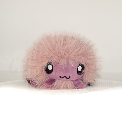 Front view of a cuttlepod plush toy, showcasing its unique form with large, cartoonish eyes, ruffled fins, and a cuddly, furry texture.