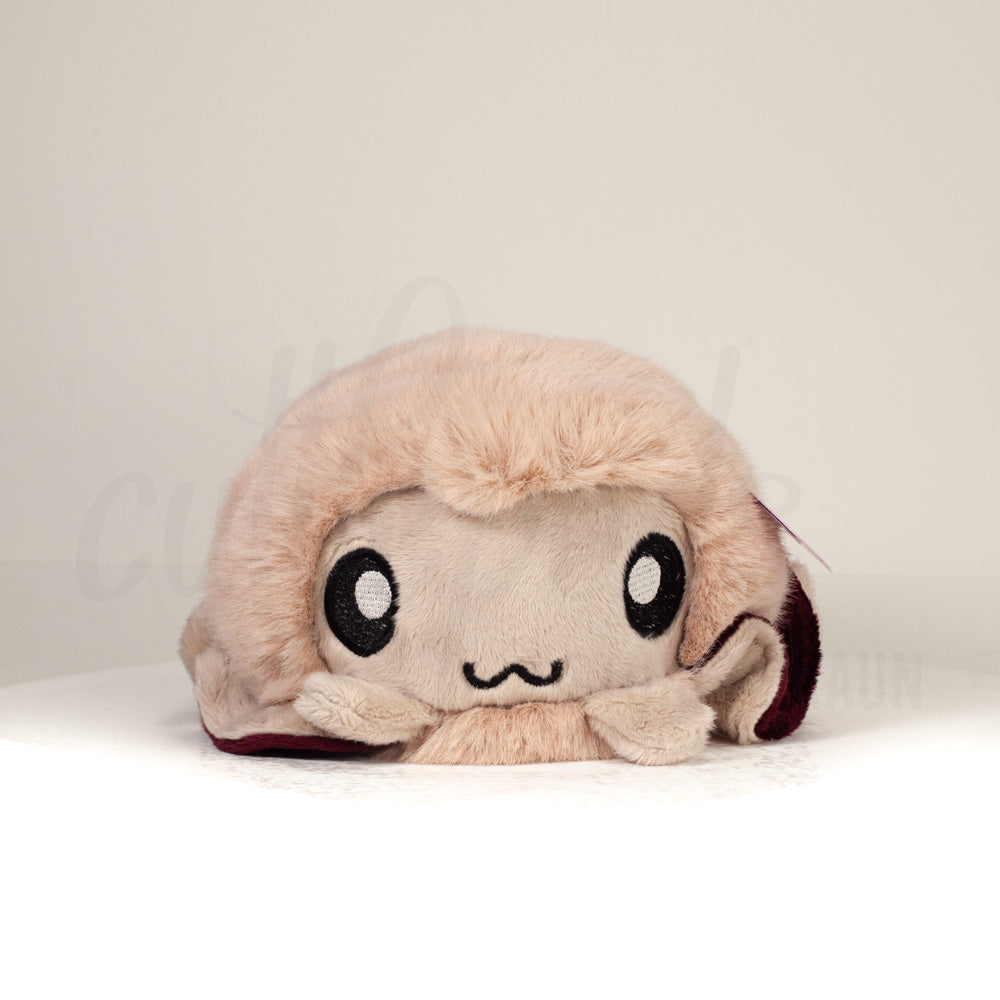 Front view of a cuttlepod plush toy, showcasing its unique form with large, cartoonish eyes, ruffled fins, and a cuddly, furry texture.