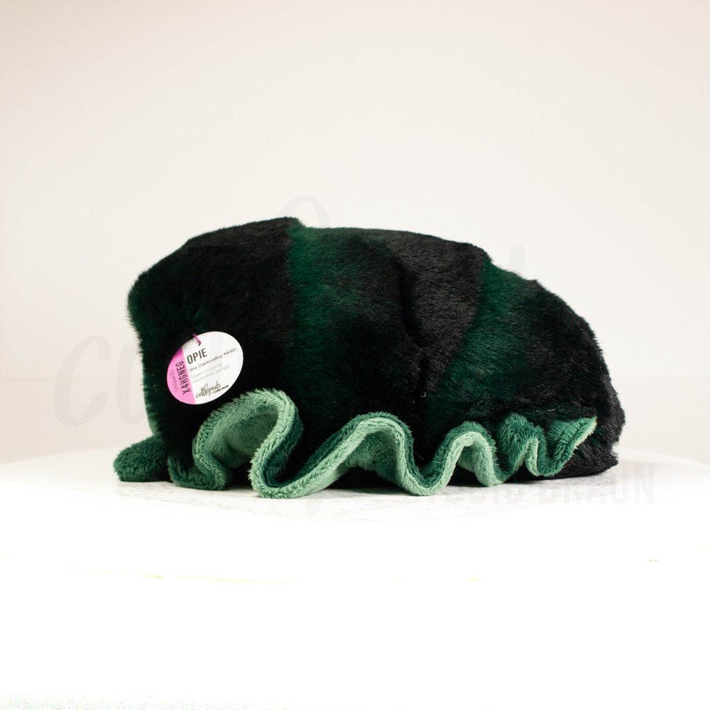 Side profile view of a cuttlepod plush toy, showcasing two-tone ruffled fins, and a cuddly, furry body.