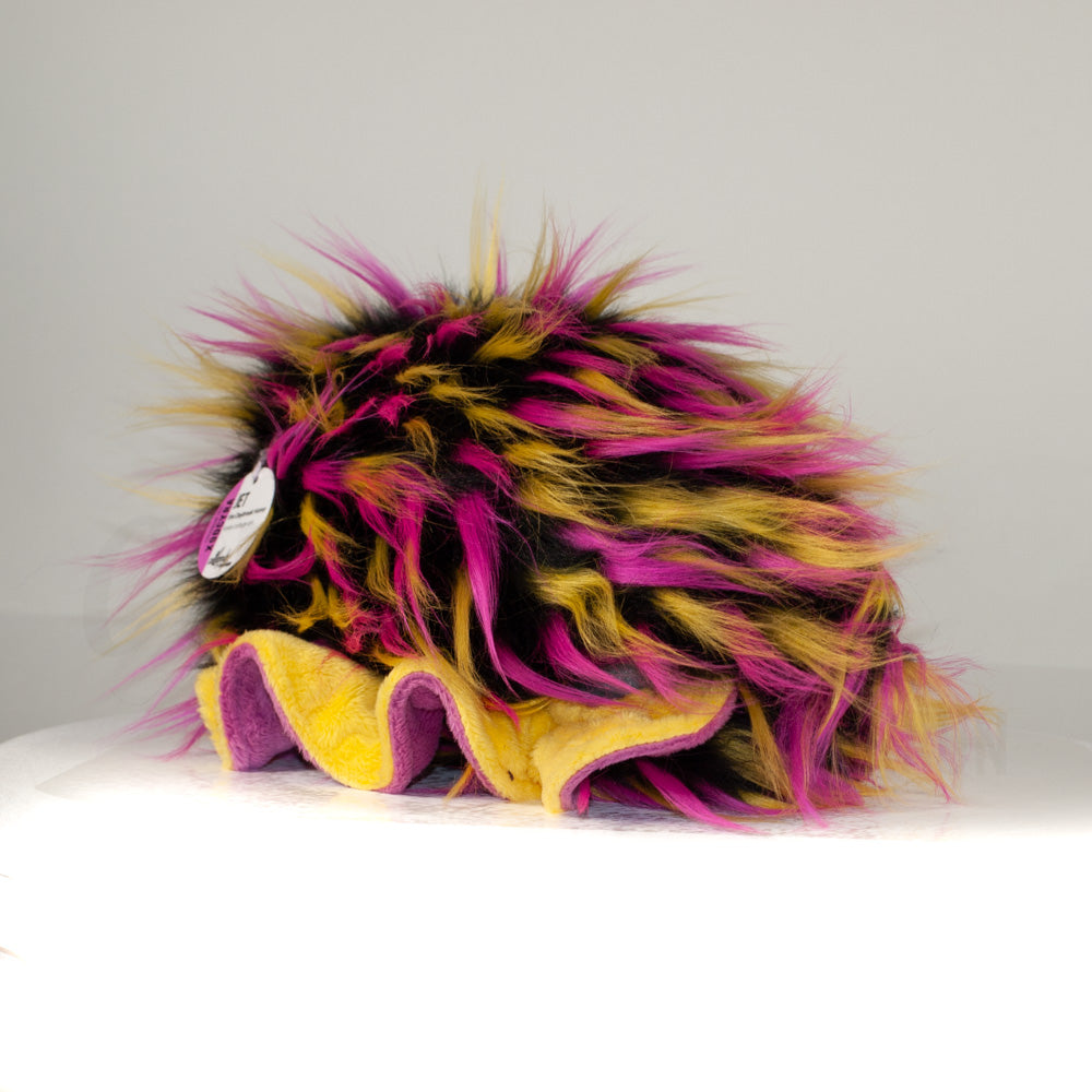 Slightly angled back view of a cuttlepod plush toy, highlighting two-tone ruffled fins, and a cuddly, furry body that comes to a soft point at the rear.