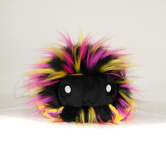 Front view of a cuttlepod plush toy, showcasing its unique form with large, cartoonish eyes, ruffled fins, and a cuddly, furry texture.