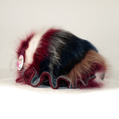 Slightly angled back view of a cuttlepod plush toy, highlighting two-tone ruffled fins, and a cuddly, furry body that comes to a soft point at the rear.