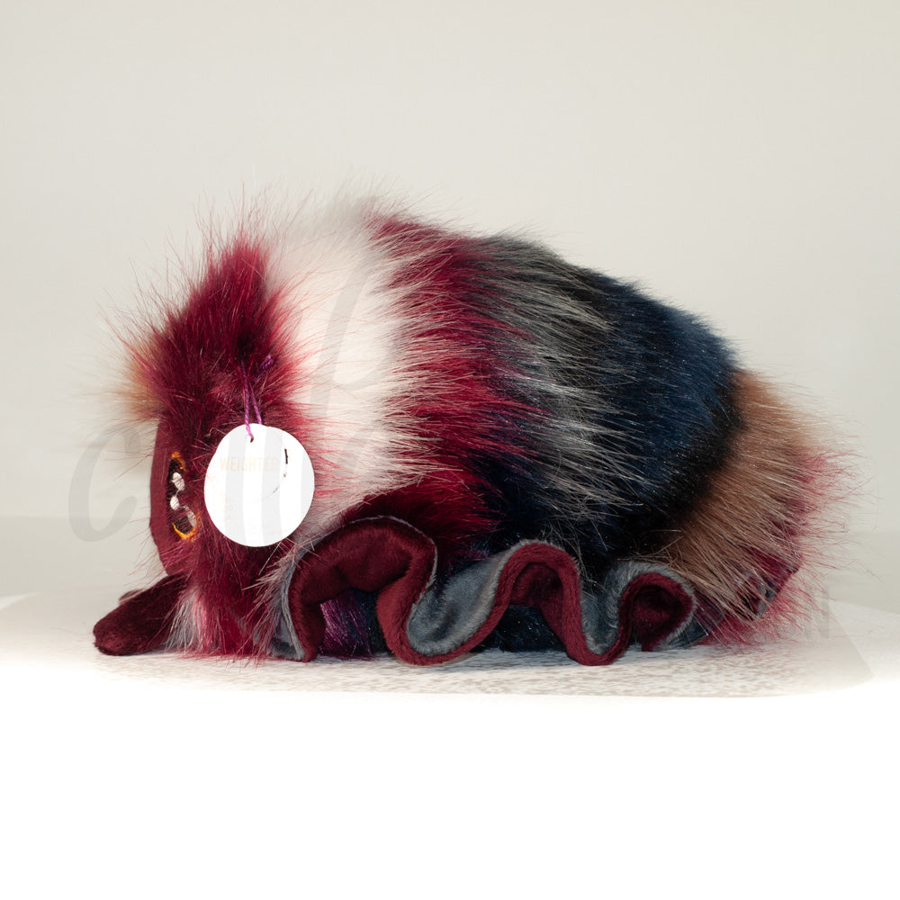 Side profile view of a cuttlepod plush toy, showcasing two-tone ruffled fins, and a cuddly, furry body.