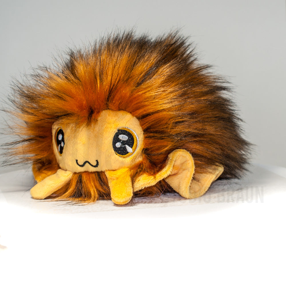 Front view of a cuttlepod plush toy, captured at a slight angle to highlight its charming features: large, cartoonish eyes, ruffled fins, and a cuddly, furry texture.