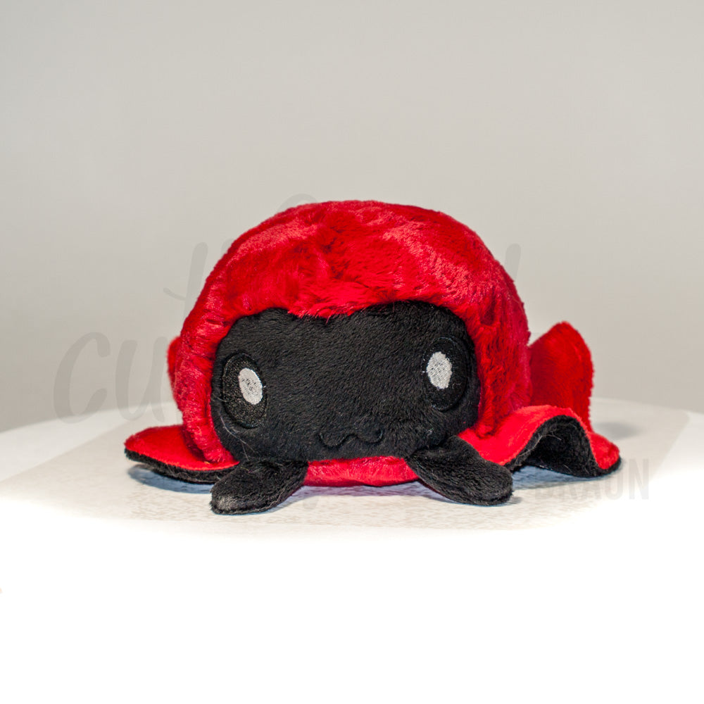 Front view of a cuttlepod plush toy, showcasing its unique form with large, cartoonish eyes, ruffled fins, and a cuddly, furry texture.