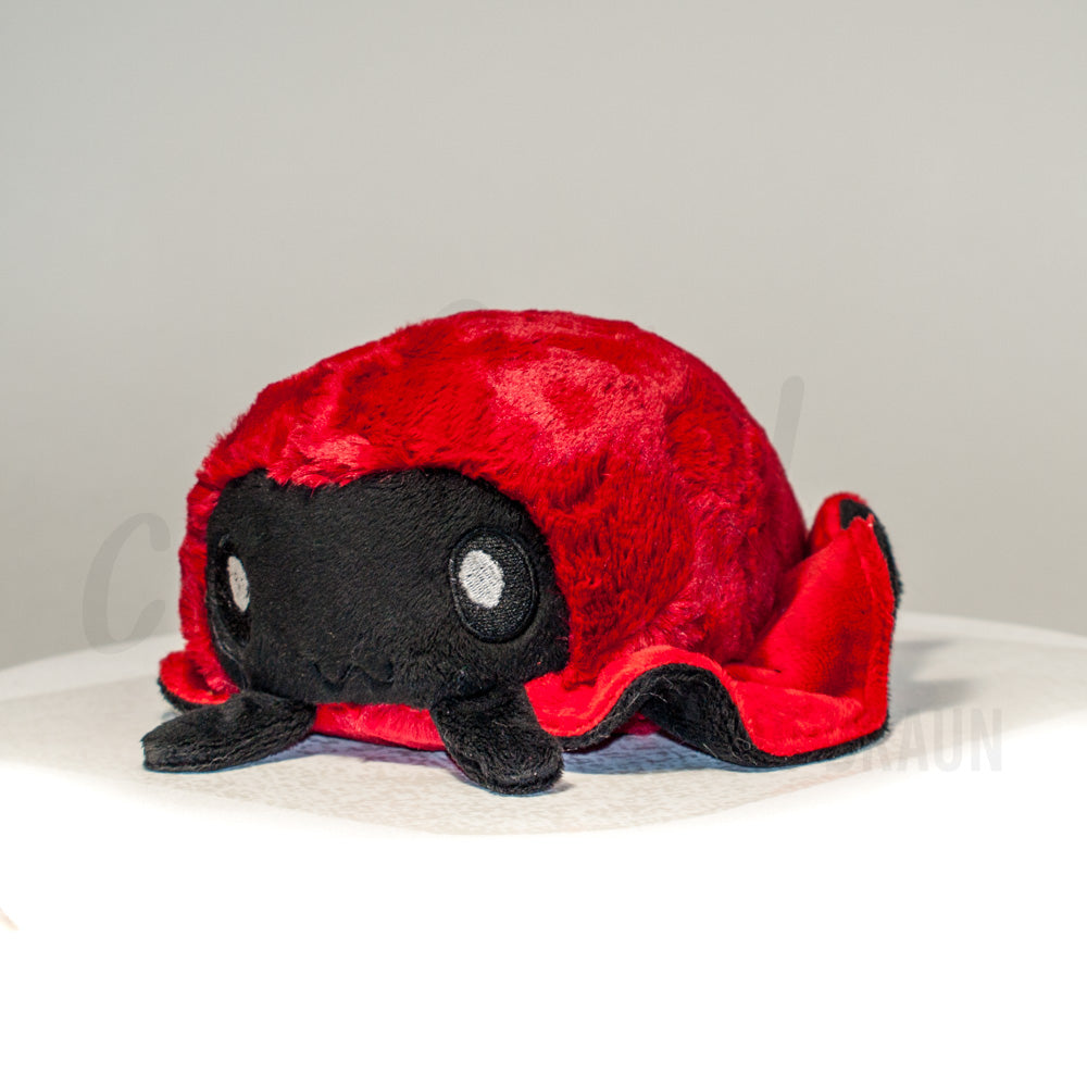 Front view of a cuttlepod plush toy, captured at a slight angle to highlight its charming features: large, cartoonish eyes, ruffled fins, and a cuddly, furry texture.