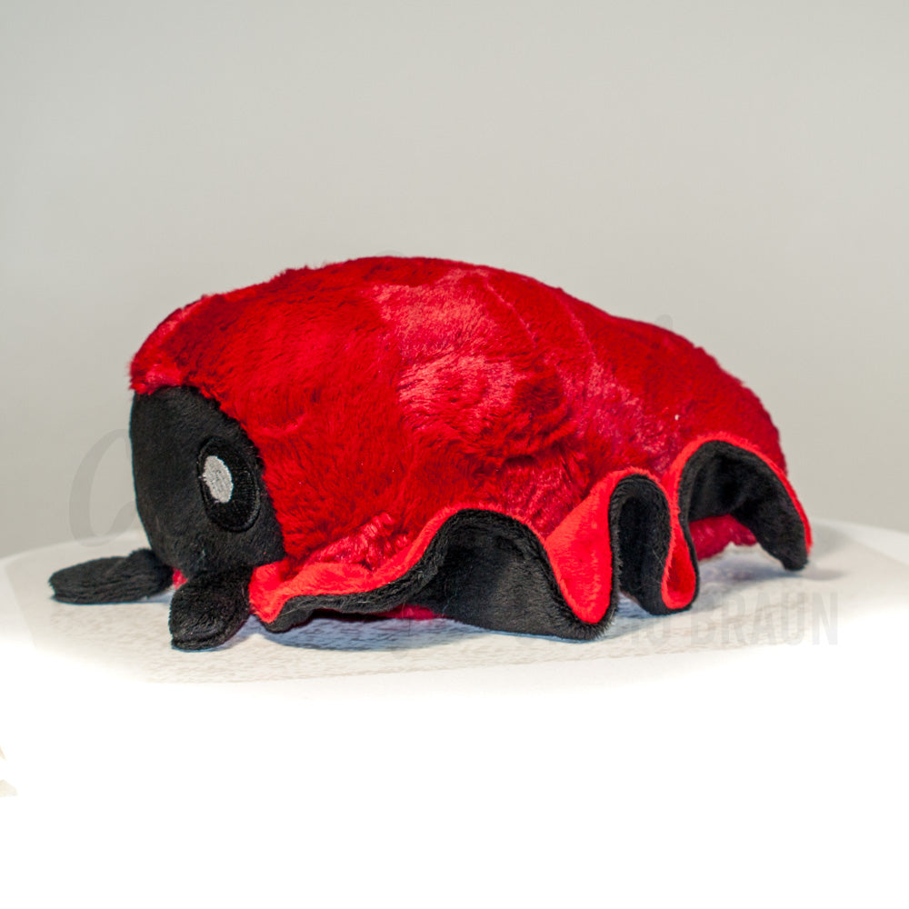 Side profile view of a cuttlepod plush toy, showcasing two-tone ruffled fins, and a cuddly, furry body.