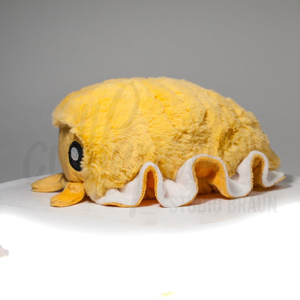 Side profile view of a cuttlepod plush toy, showcasing two-tone ruffled fins, and a cuddly, furry body.