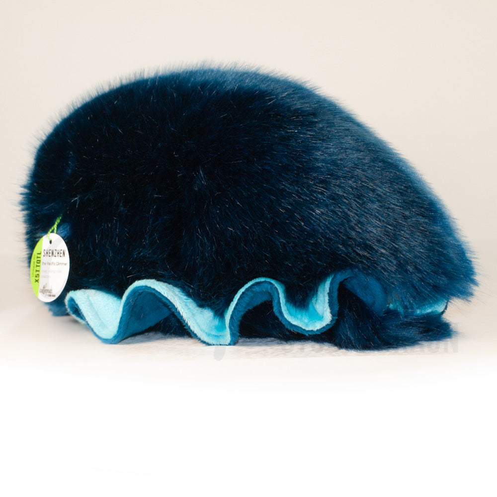 Slightly angled back view of a cuttlepod plush toy, highlighting two-tone ruffled fins, and a cuddly, furry body that comes to a soft point at the rear.