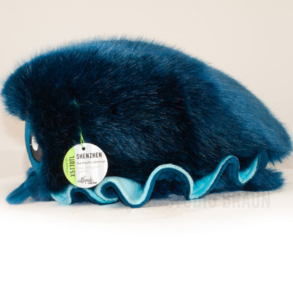 Side profile view of a cuttlepod plush toy, showcasing two-tone ruffled fins, and a cuddly, furry body.