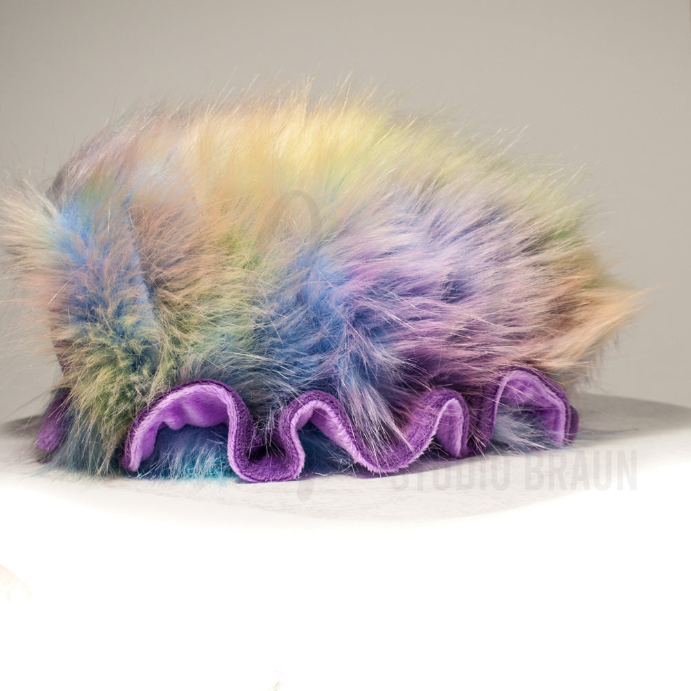 Side profile view of a cuttlepod plush toy, showcasing two-tone ruffled fins, and a cuddly, furry body.