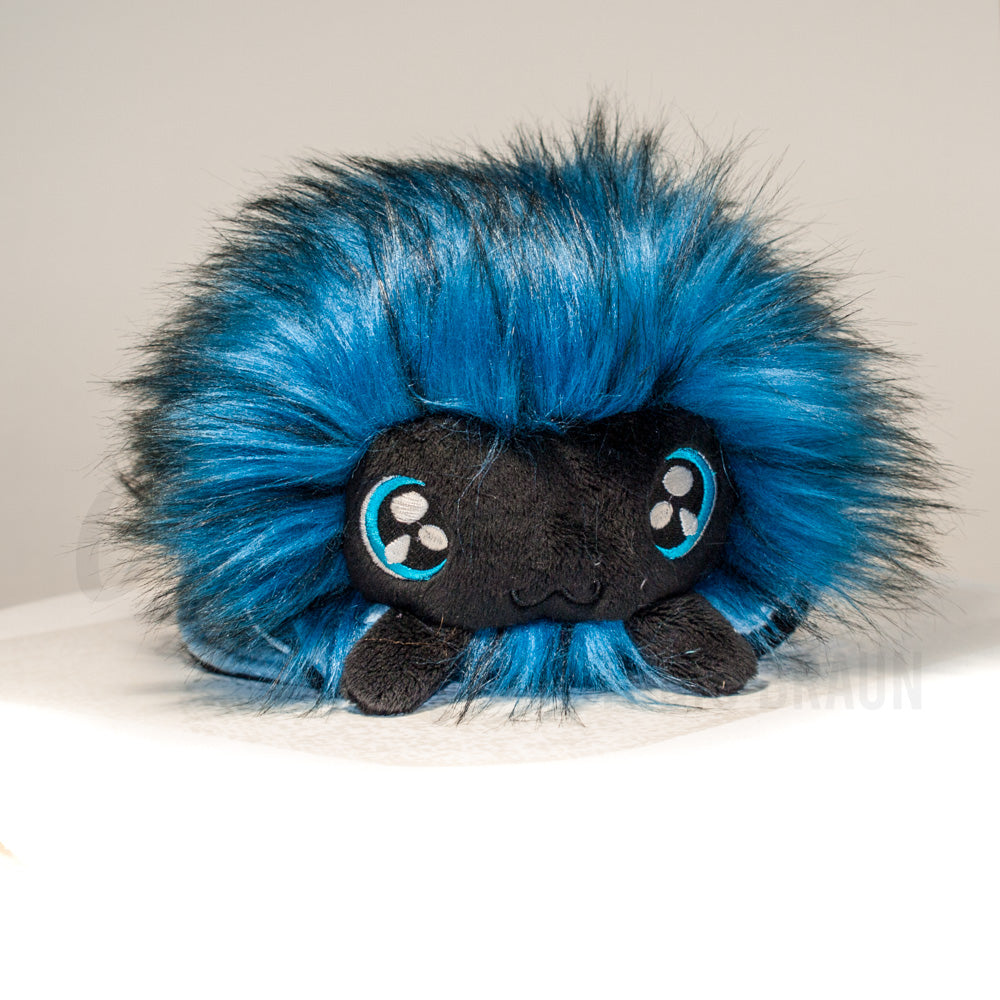 Front view of a cuttlepod plush toy, showcasing its unique form with large, cartoonish eyes, ruffled fins, and a cuddly, furry texture.