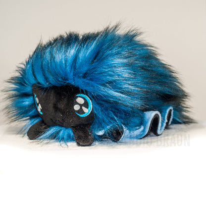 Front view of a cuttlepod plush toy, captured at a slight angle to highlight its charming features: large, cartoonish eyes, ruffled fins, and a cuddly, furry texture.