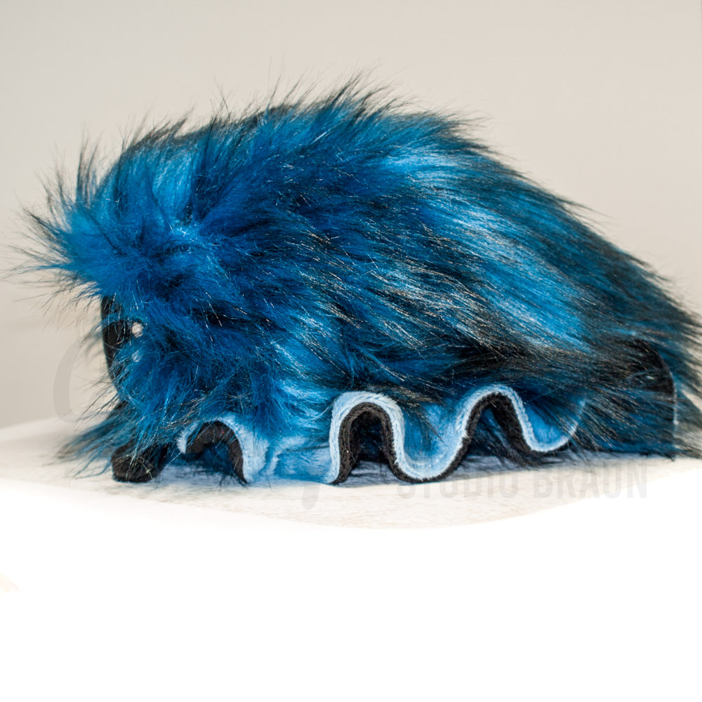 Side profile view of a cuttlepod plush toy, showcasing two-tone ruffled fins, and a cuddly, furry body.