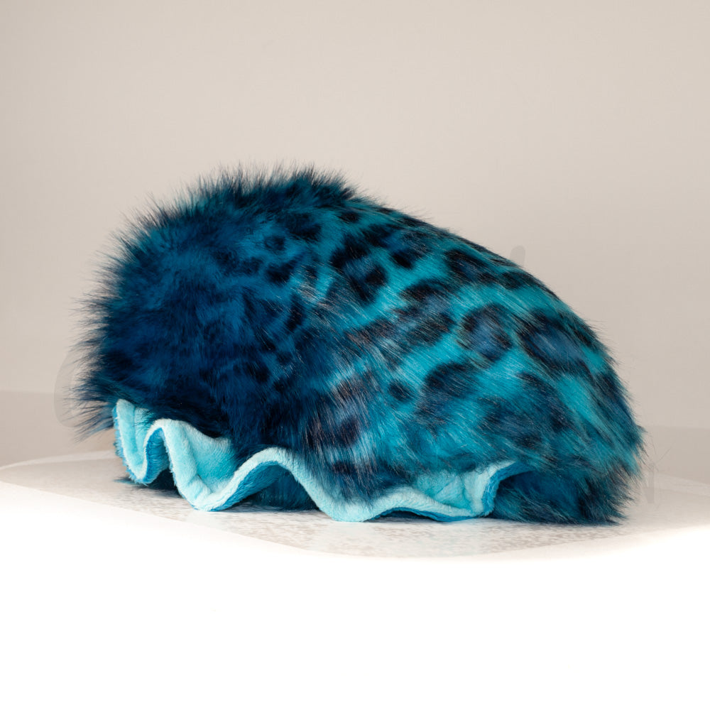 Slightly angled back view of a cuttlepod plush toy, highlighting two-tone ruffled fins, and a cuddly, furry body that comes to a soft point at the rear.