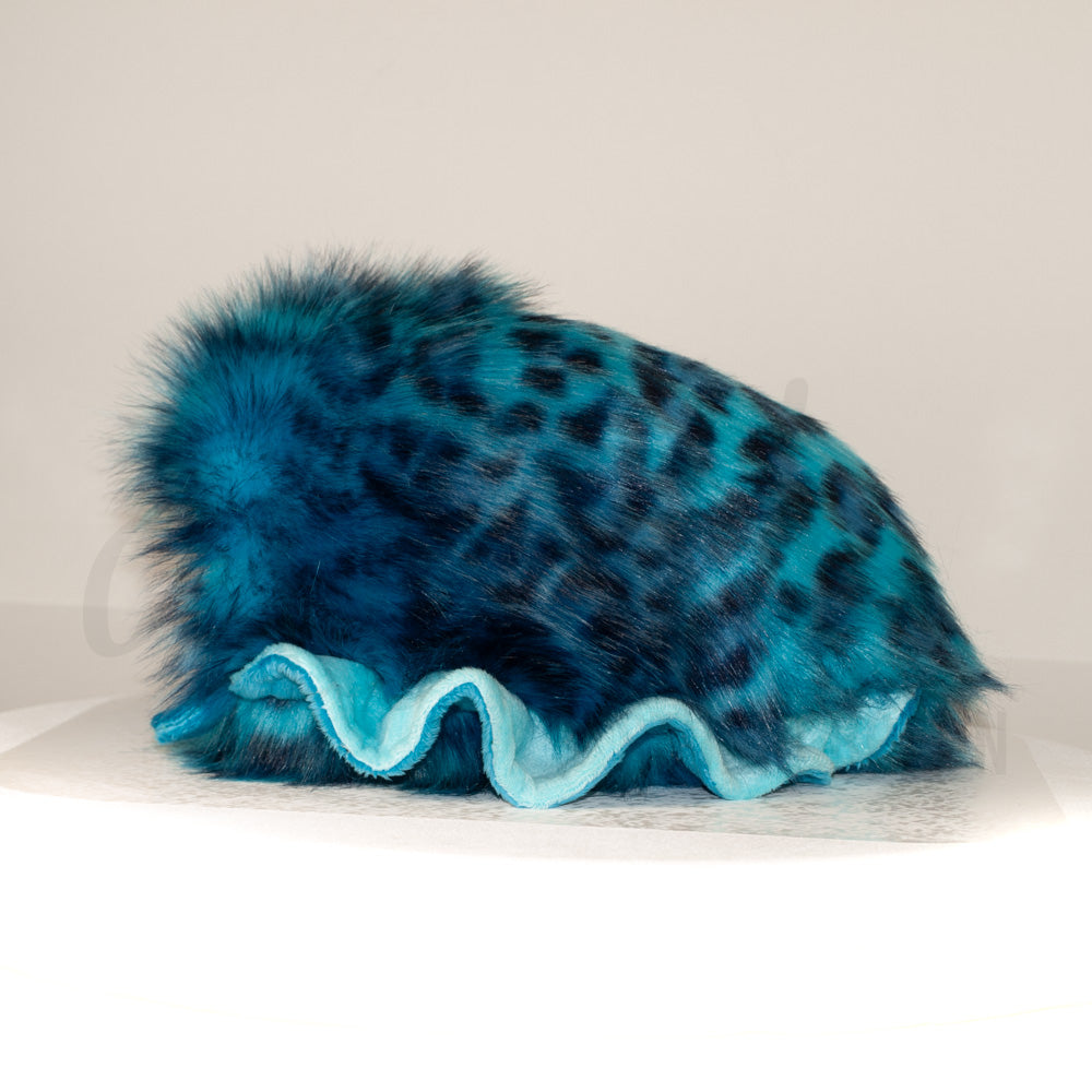 Side profile view of a cuttlepod plush toy, showcasing two-tone ruffled fins, and a cuddly, furry body.