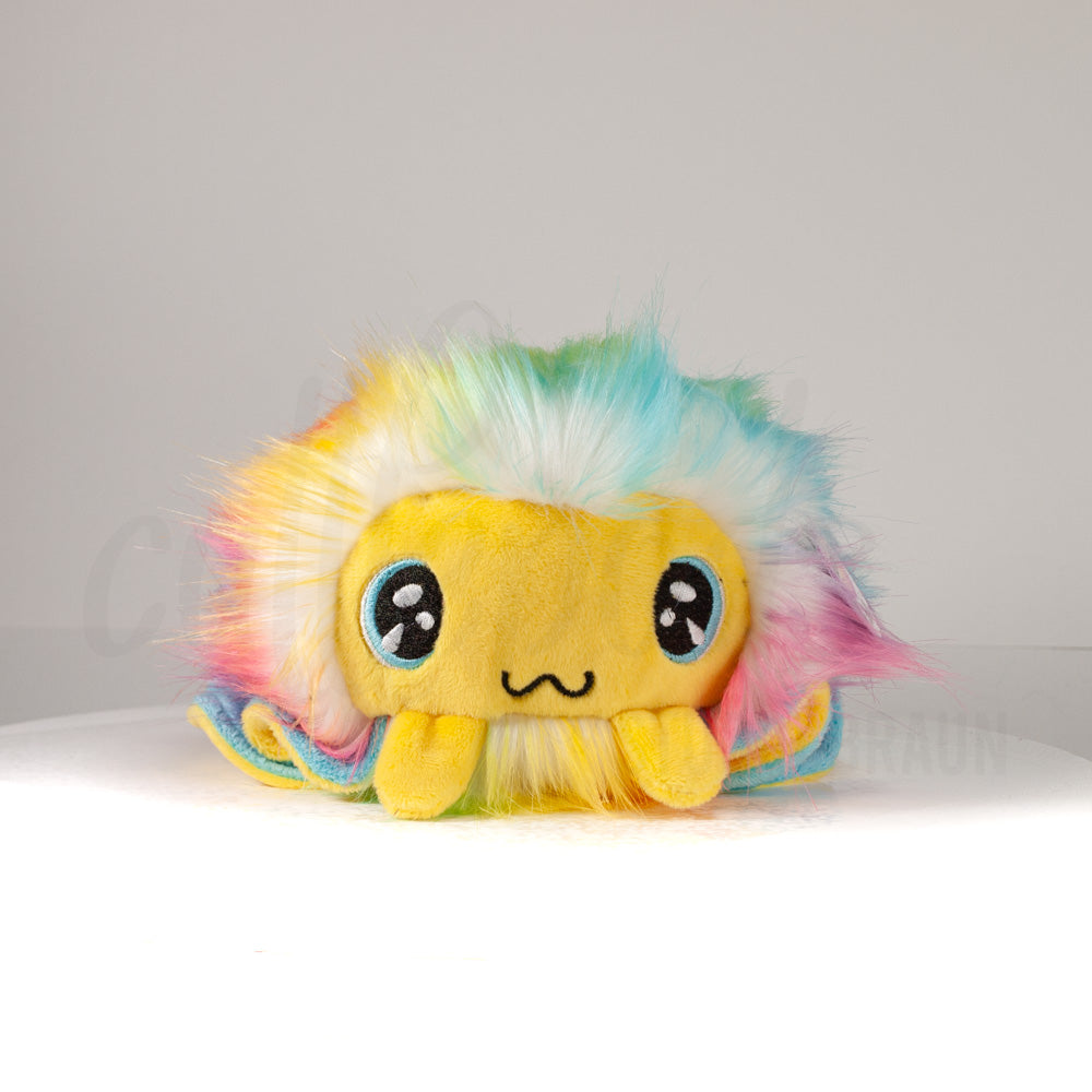 Front view of a cuttlepod plush toy, showcasing its unique form with large, cartoonish eyes, ruffled fins, and a cuddly, furry texture.