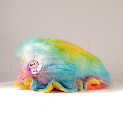 Side profile view of a cuttlepod plush toy, showcasing two-tone ruffled fins, and a cuddly, furry body.