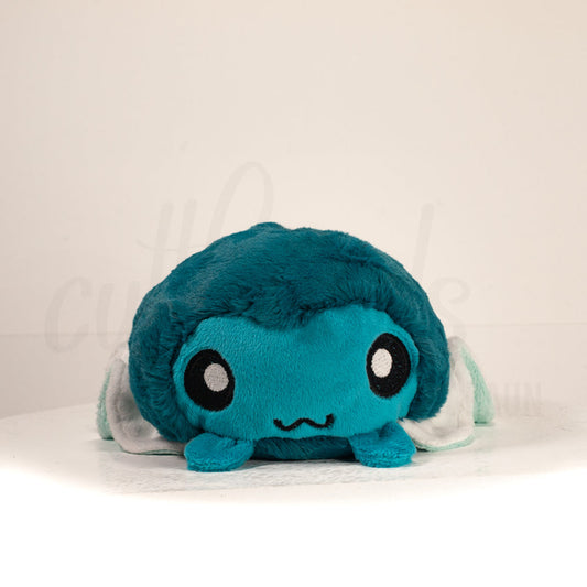 Front view of a cuttlepod plush toy, showcasing its unique form with large, cartoonish eyes, ruffled fins, and a cuddly, furry texture.