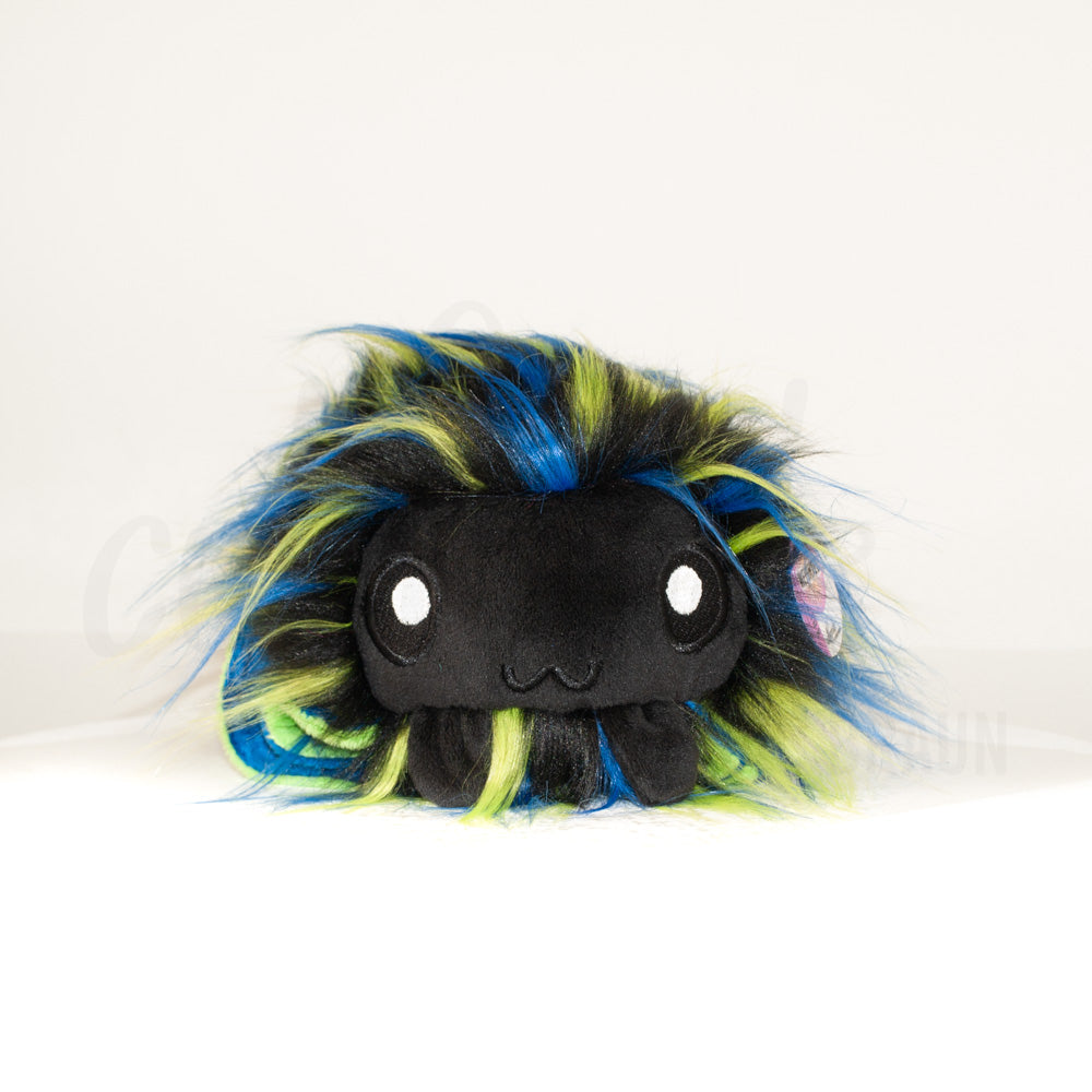 Front view of a cuttlepod plush toy, showcasing its unique form with large, cartoonish eyes, ruffled fins, and a cuddly, furry texture.