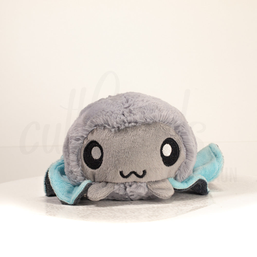 Front view of a cuttlepod plush toy, showcasing its unique form with large, cartoonish eyes, ruffled fins, and a cuddly, furry texture.