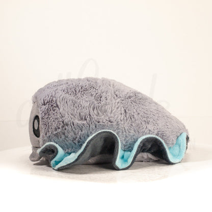 Side profile view of a cuttlepod plush toy, showcasing two-tone ruffled fins, and a cuddly, furry body.