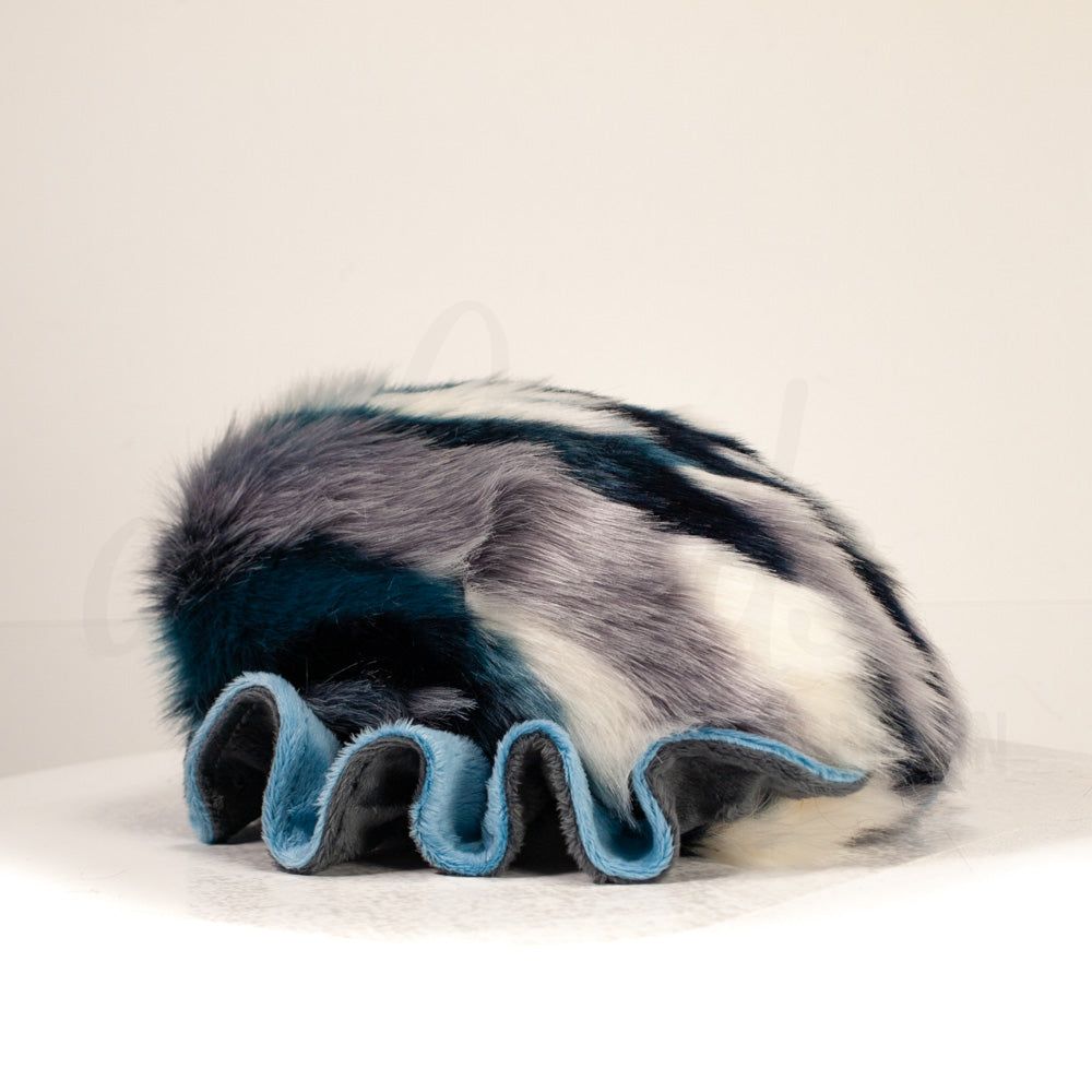 Slightly angled back view of a cuttlepod plush toy, highlighting two-tone ruffled fins, and a cuddly, furry body that comes to a soft point at the rear.