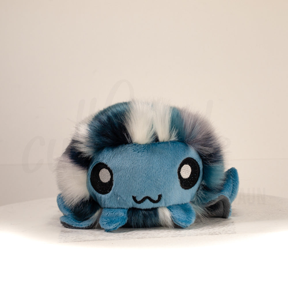 Front view of a cuttlepod plush toy, showcasing its unique form with large, cartoonish eyes, ruffled fins, and a cuddly, furry texture.