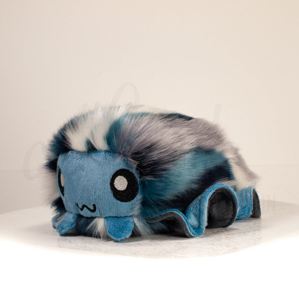 Front view of a cuttlepod plush toy, captured at a slight angle to highlight its charming features: large, cartoonish eyes, ruffled fins, and a cuddly, furry texture.