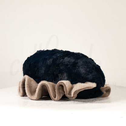 Slightly angled back view of a cuttlepod plush toy, highlighting two-tone ruffled fins, and a cuddly, furry body that comes to a soft point at the rear.