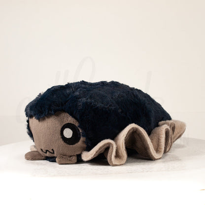 Front view of a cuttlepod plush toy, captured at a slight angle to highlight its charming features: large, cartoonish eyes, ruffled fins, and a cuddly, furry texture.