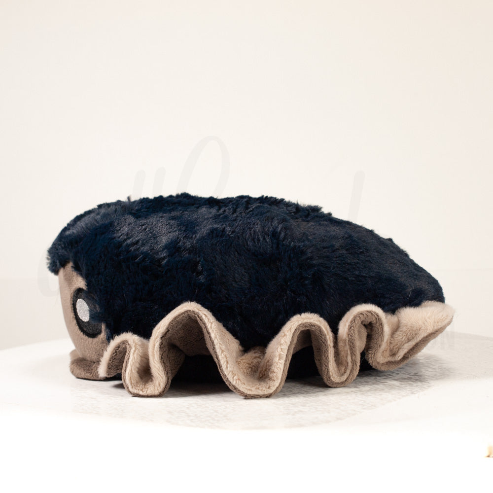 Side profile view of a cuttlepod plush toy, showcasing two-tone ruffled fins, and a cuddly, furry body.