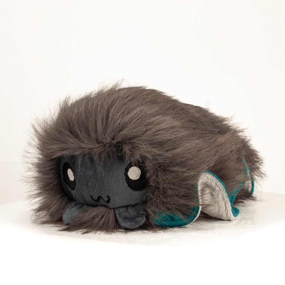 Front view of a cuttlepod plush toy, captured at a slight angle to highlight its charming features: large, cartoonish eyes, ruffled fins, and a cuddly, furry texture.