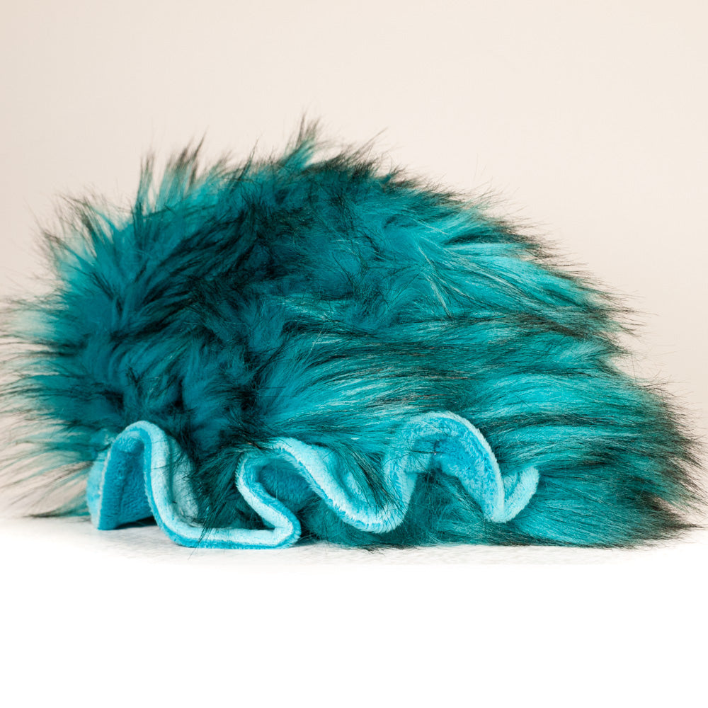 Slightly angled back view of a cuttlepod plush toy, highlighting two-tone ruffled fins, and a cuddly, furry body that comes to a soft point at the rear.