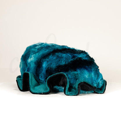 Slightly angled back view of a cuttlepod plush toy, highlighting two-tone ruffled fins, and a cuddly, furry body that comes to a soft point at the rear.