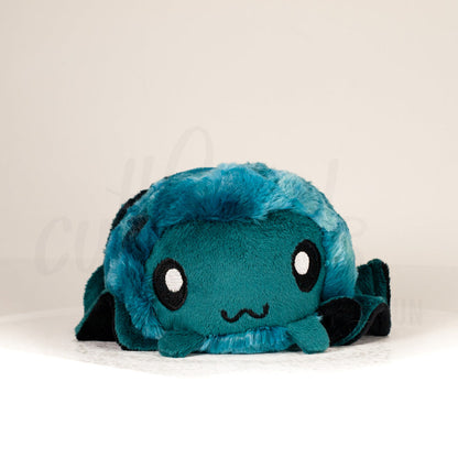 Front view of a cuttlepod plush toy, showcasing its unique form with large, cartoonish eyes, ruffled fins, and a cuddly, furry texture.