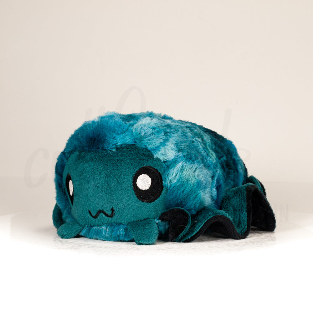 Front view of a cuttlepod plush toy, captured at a slight angle to highlight its charming features: large, cartoonish eyes, ruffled fins, and a cuddly, furry texture.