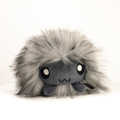 Side profile view of a cuttlepod plush toy, showcasing two-tone ruffled fins, and a cuddly, furry body.