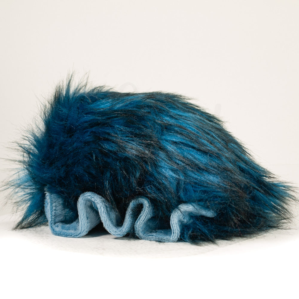 Slightly angled back view of a cuttlepod plush toy, highlighting two-tone ruffled fins, and a cuddly, furry body that comes to a soft point at the rear.