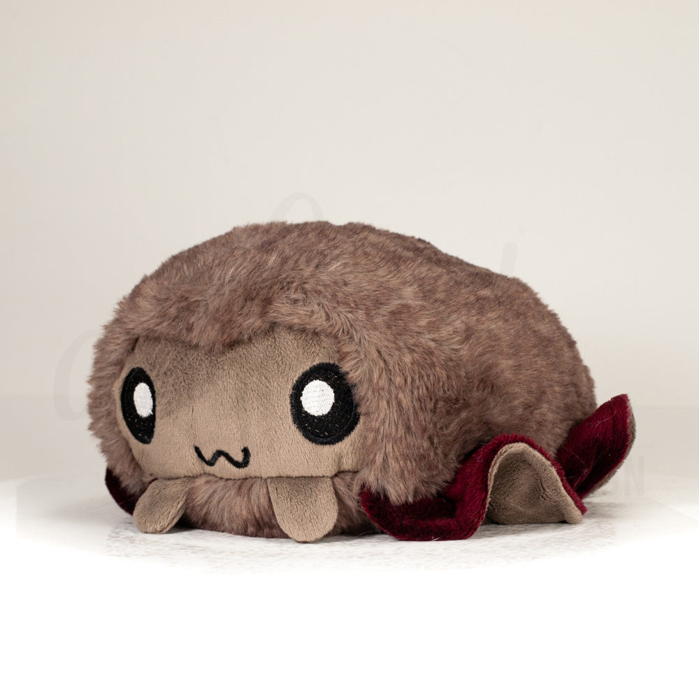 Front view of a cuttlepod plush toy, captured at a slight angle to highlight its charming features: large, cartoonish eyes, ruffled fins, and a cuddly, furry texture.