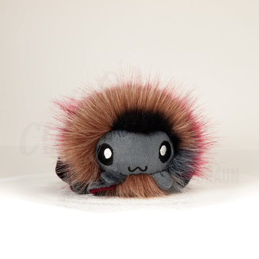 Front view of a cuttlepod plush toy, showcasing its unique form with large, cartoonish eyes, ruffled fins, and a cuddly, furry texture.